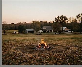 Wide view of a rural property at dusk with a small burn pile in the foreground a safe distance from the farmhouse in the background